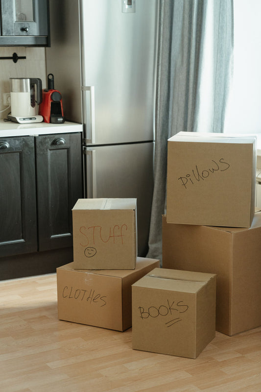 Moving boxes labeled stuff and pillows in a first apartment kitchen